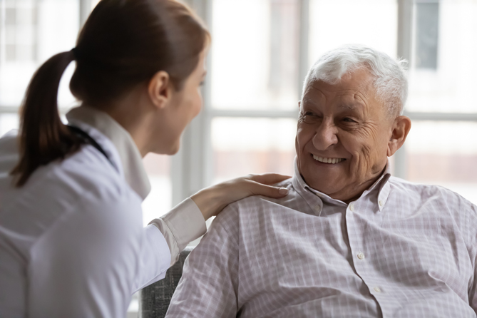 Caring geriatric nurse in white coat cares for elderly man