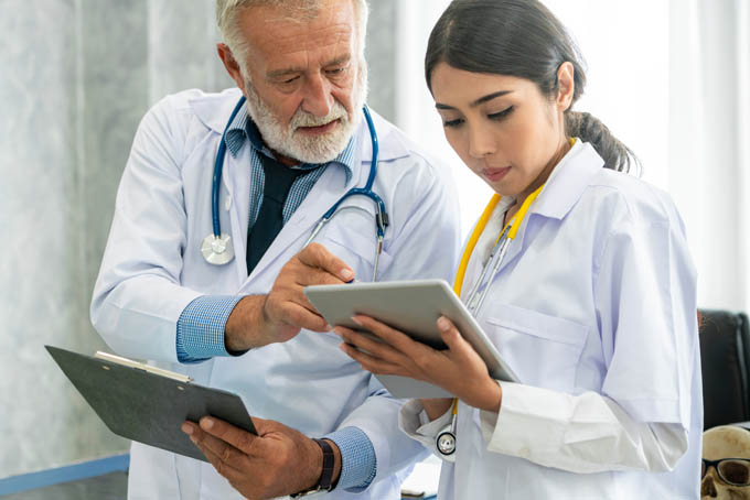 Senior male doctor using tablet computer while discussing with another doctor at the hospital