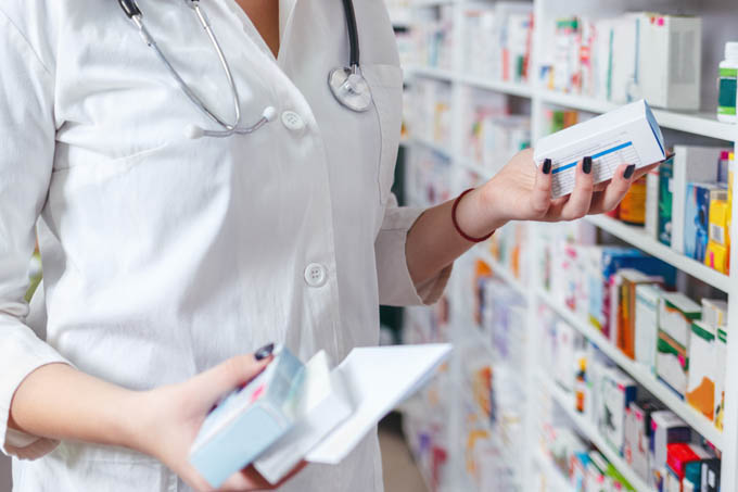 Woman pharmacist holding prescription checking medicine in pharmacy