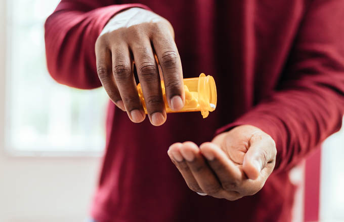 Man pouring pills from prescription bottle into hands