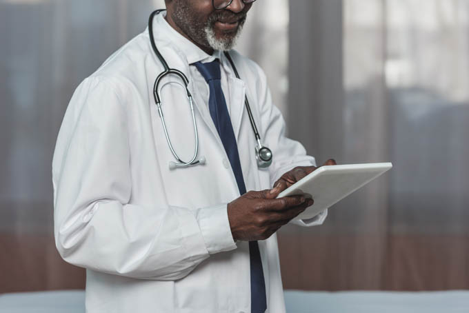 Cropped image of mature doctor looking at tablet