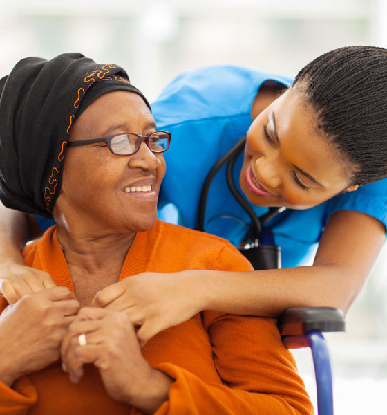 Woman nurse hugging an elderly patient in a wheelchair.