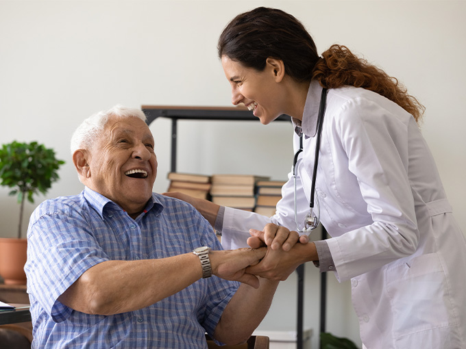 Happy elderly male patient talking to female doctor