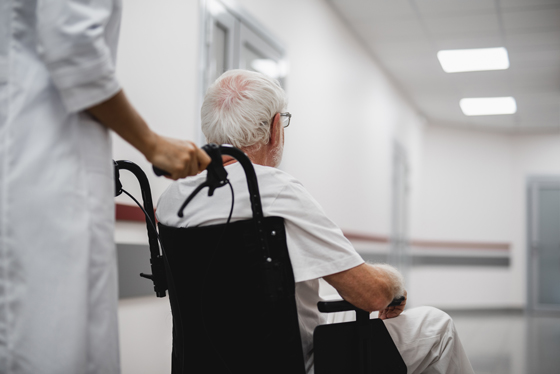 Doctor walking with elderly man in hospital hallway