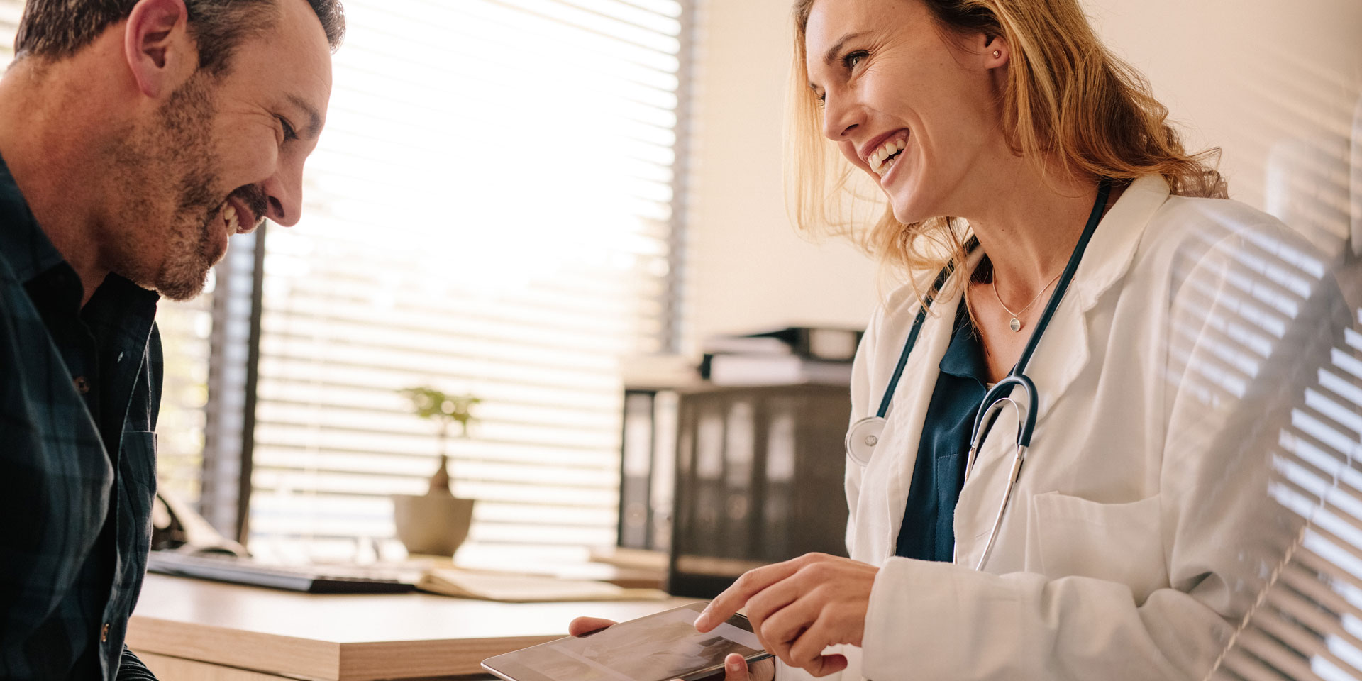 Female doctor talking and smiling with a male patient