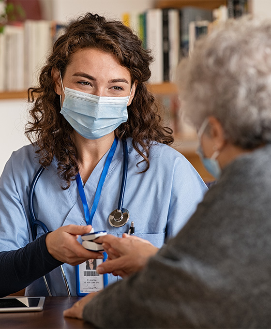Female doctor wearing mask taking vitals of an elderly patient