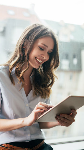 Business woman smiling down at a tablet in a modern office