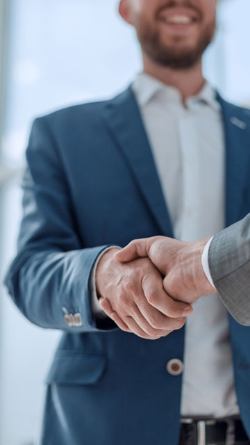 Two male business partners shaking hands in an office.