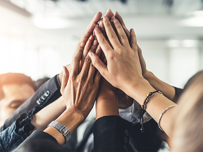 Happy businesspeople joining hands together to signify teamwork