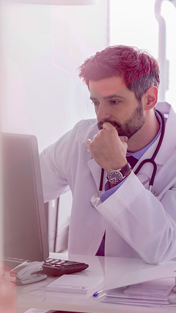 Male doctor concentrating looking at a computer screen