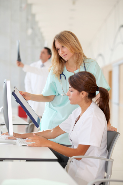 Nurse with intern working in front of computer