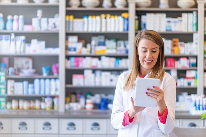 Smiling female pharmacist scrolling on a tablet in a pharmacy