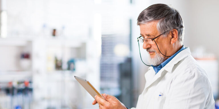 Male doctor wearing glasses using a tablet in a lab