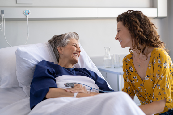 Woman visiting senior mother in hospital bed