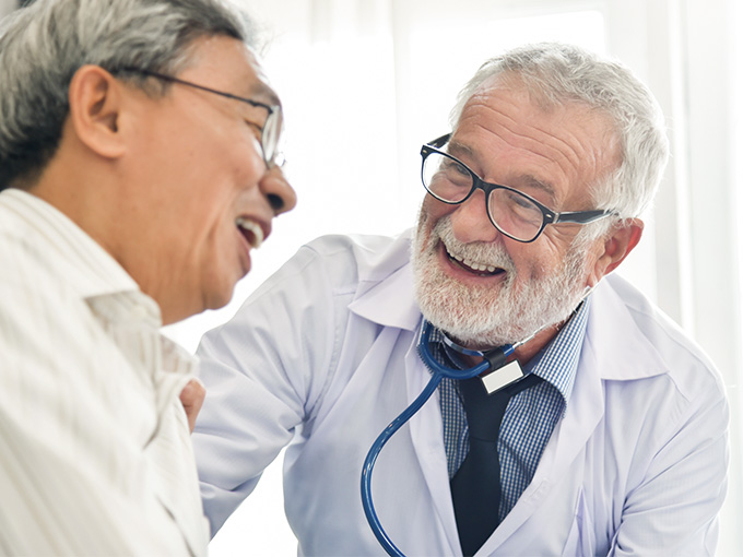 Gray haired doctor laughing with his patient